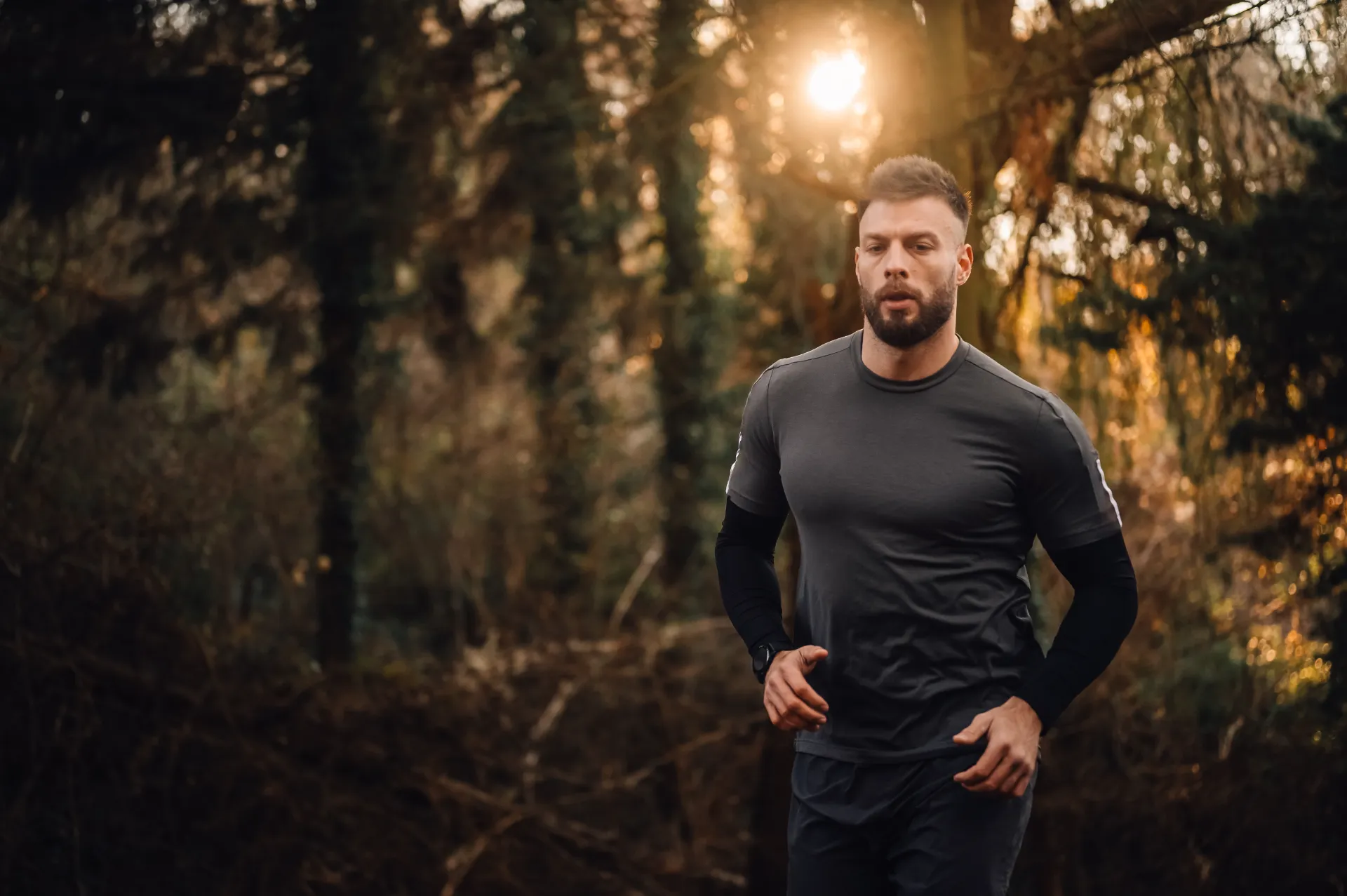 determined male athlete running in forest at sunse utc